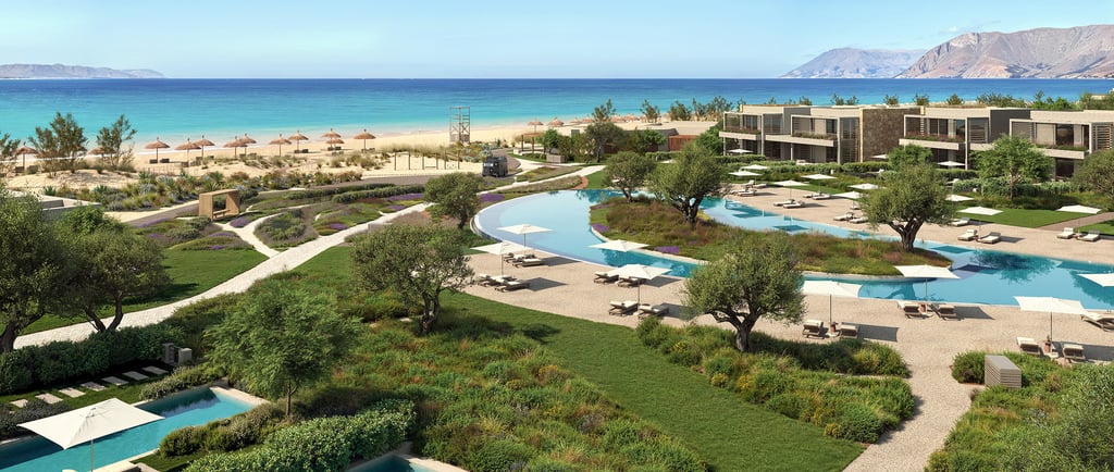 Luxury Ikos resort with turquoise pools, modern villas, and ocean views in a coastal landscape.