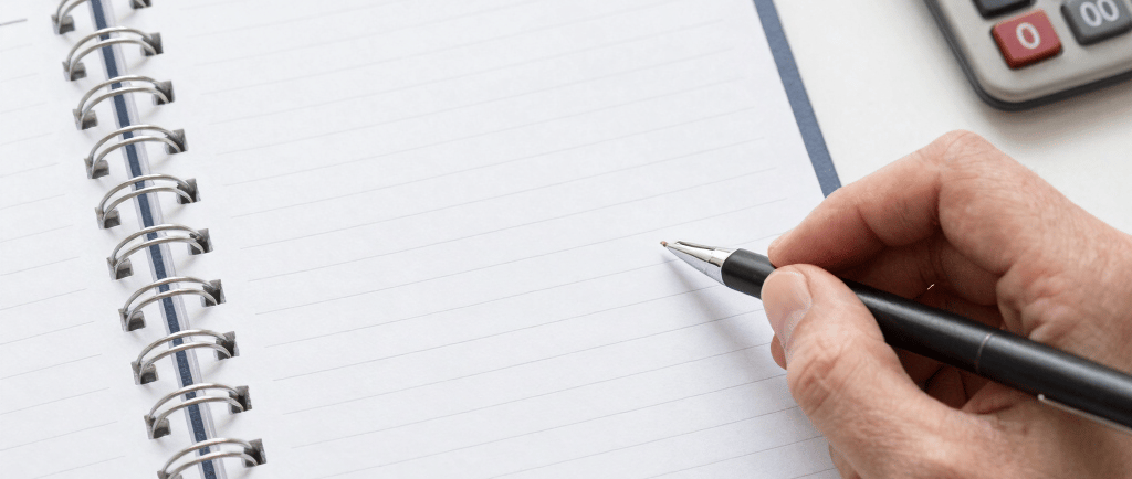 A cozy workspace with a laptop, notebook, and a cup of coffee, bathed in natural light.