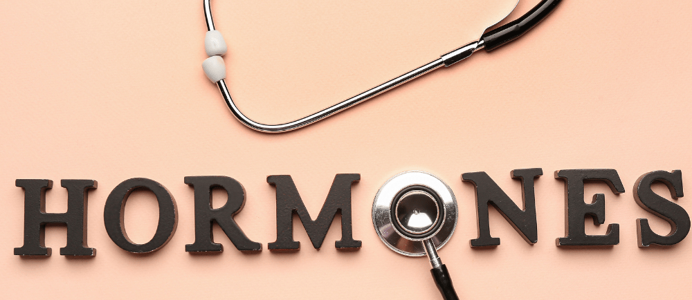 the word "hormones" wrttem down with a stethoscope  as the "o". background pink
