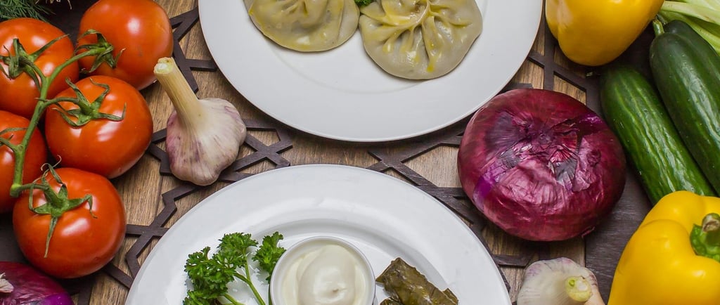 Two plates of fresh Mediterranean‑style dishes surrounded by colorful vegetables, including bell peppers, tomatoes 