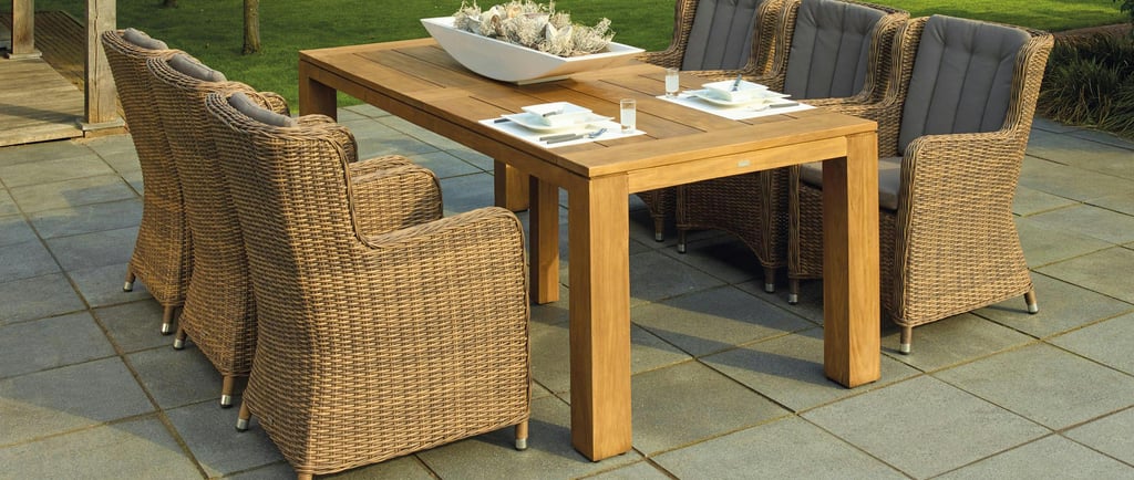 Outdoor patio dining area featuring a wooden table set with white plates and glasses