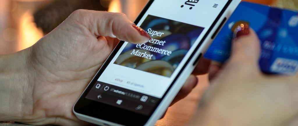 A person using a smartphone and credit card for mobile online shopping at an ecommerce store.