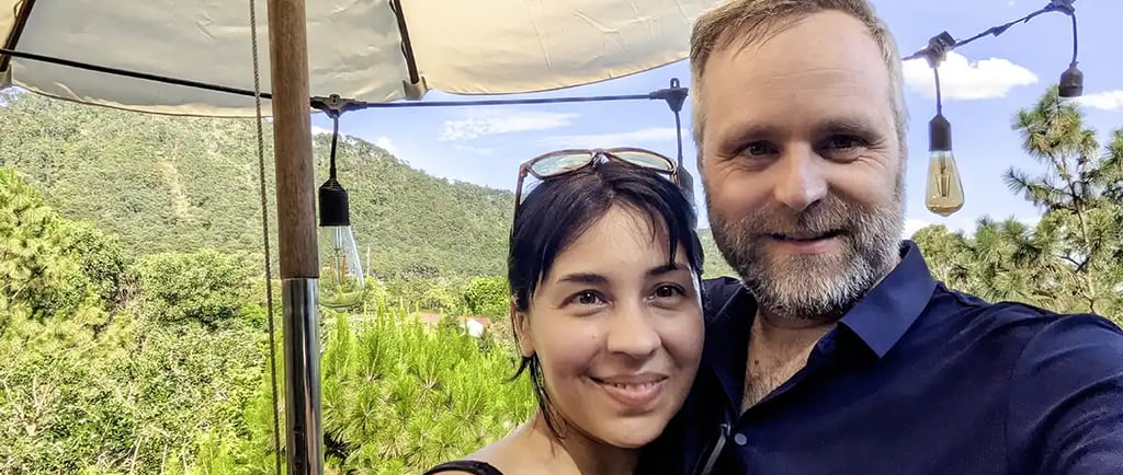 A couple standing together in a forested area in Vietnam during post surgery recovery