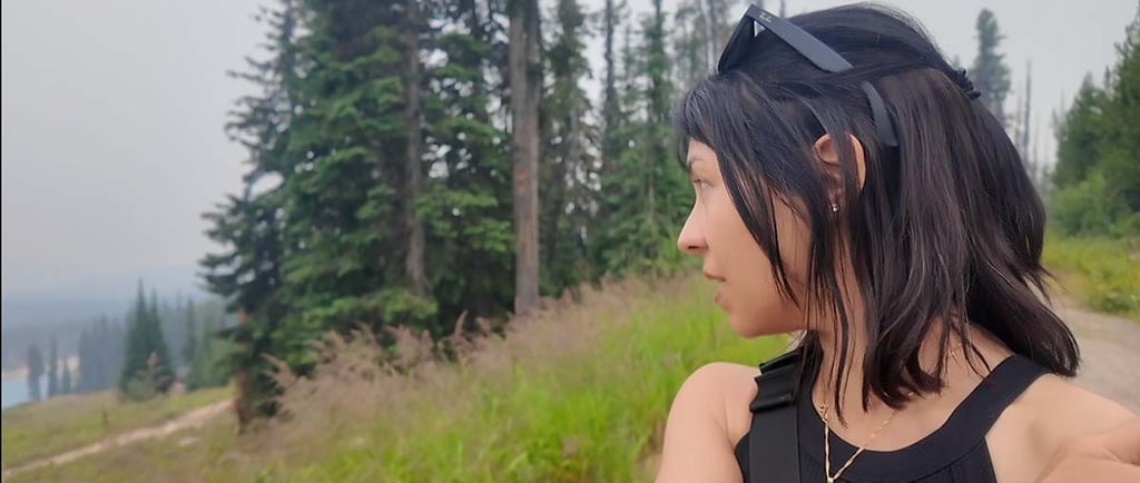 Woman looking across a smoky mountain landscape with evergreen trees in Big White, British Columbia.