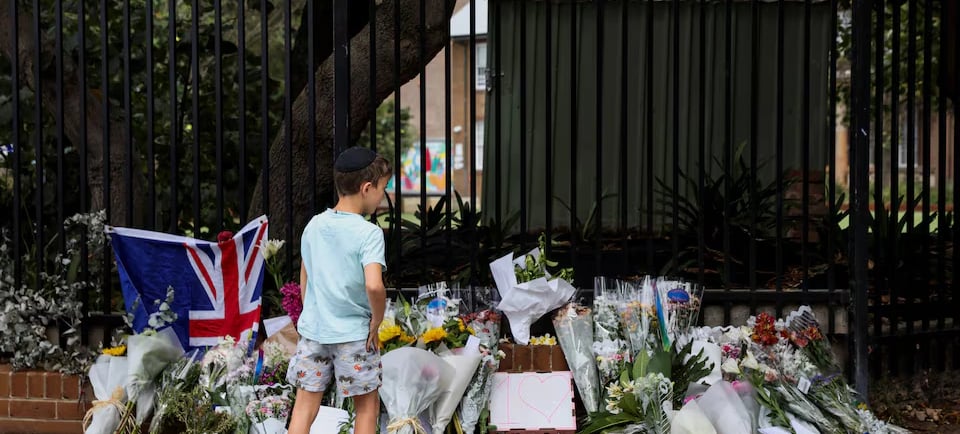 a man walking past a fence with flowers and flowers