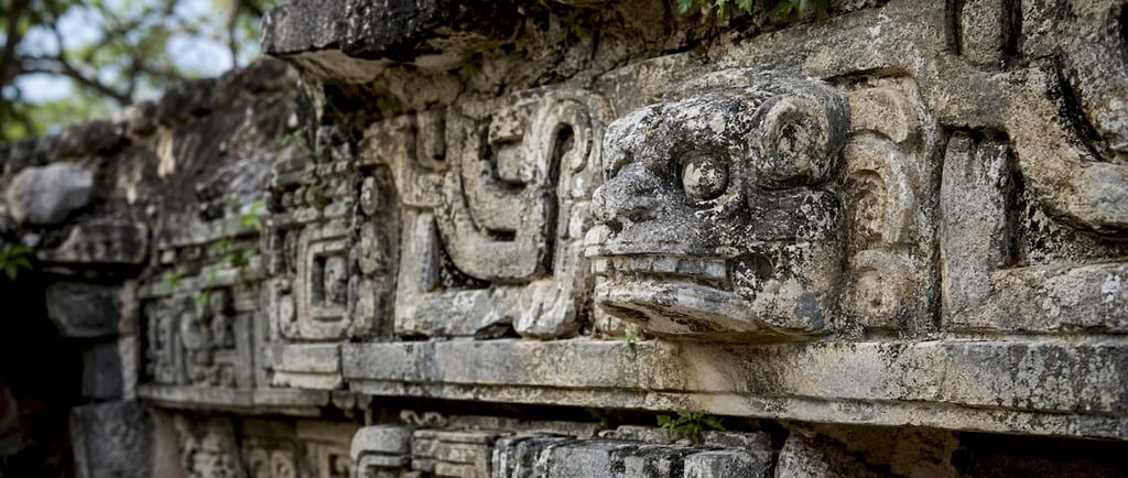 Ancient Mayan stone carvings and jaguar head sculpture at the archaeological ruins of Chichen Itza.