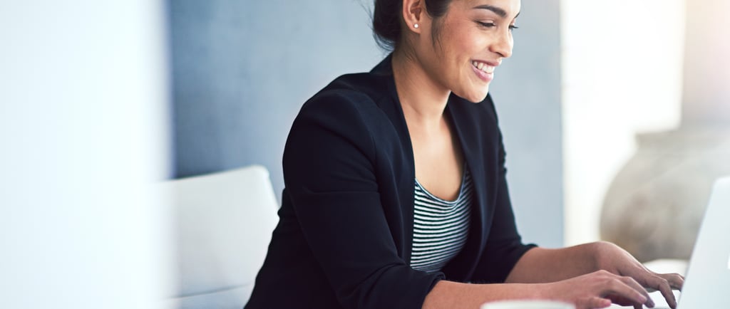 Mulher de negócios sorridente trabalhando em um laptop em um escritório moderno e iluminado, com uma