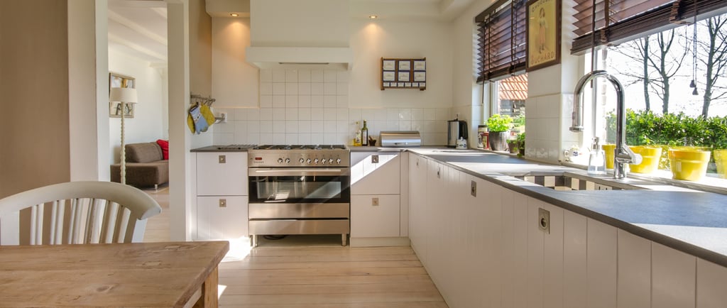 Calm Mediterranean kitchen with a natural stone worktop and simple wood cabinetry in warm morning li