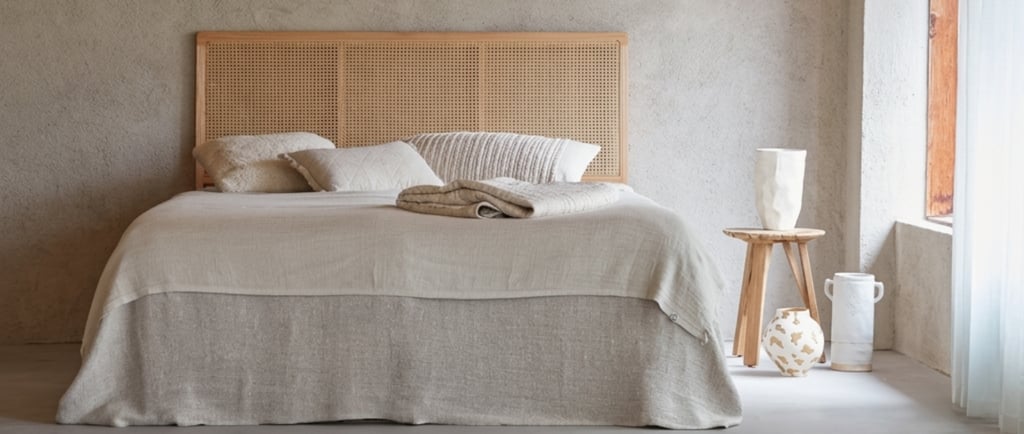 linen bedding, wood headboard, and plaster wall.