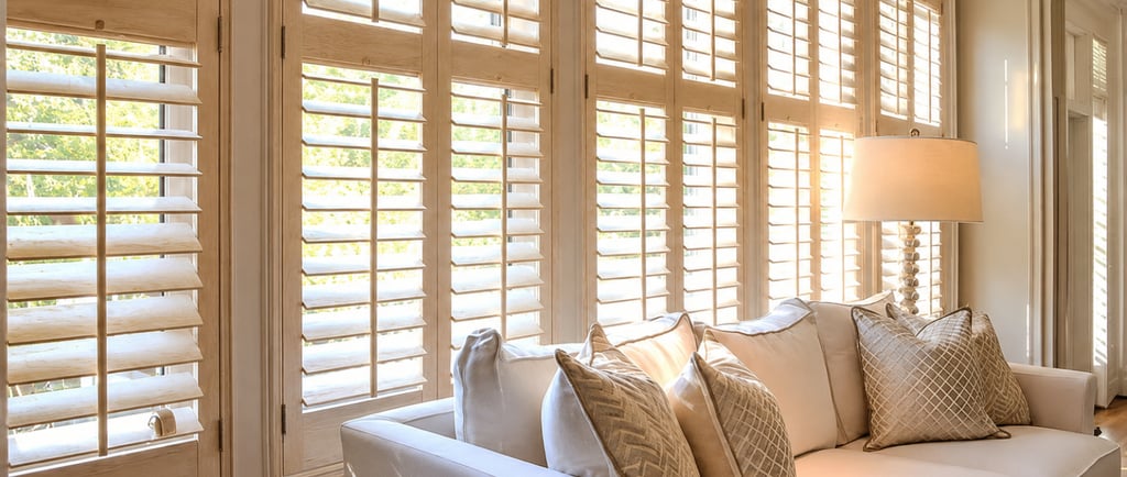 Shutters filtering direct midday light onto a plaster wall.