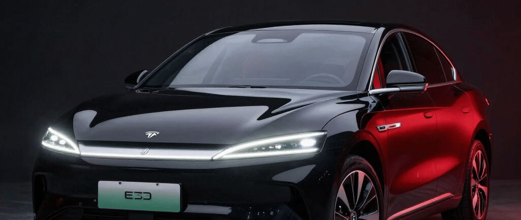 A sleek, futuristic Chinese electric car illuminated under moody dark lighting with subtle red accents.
