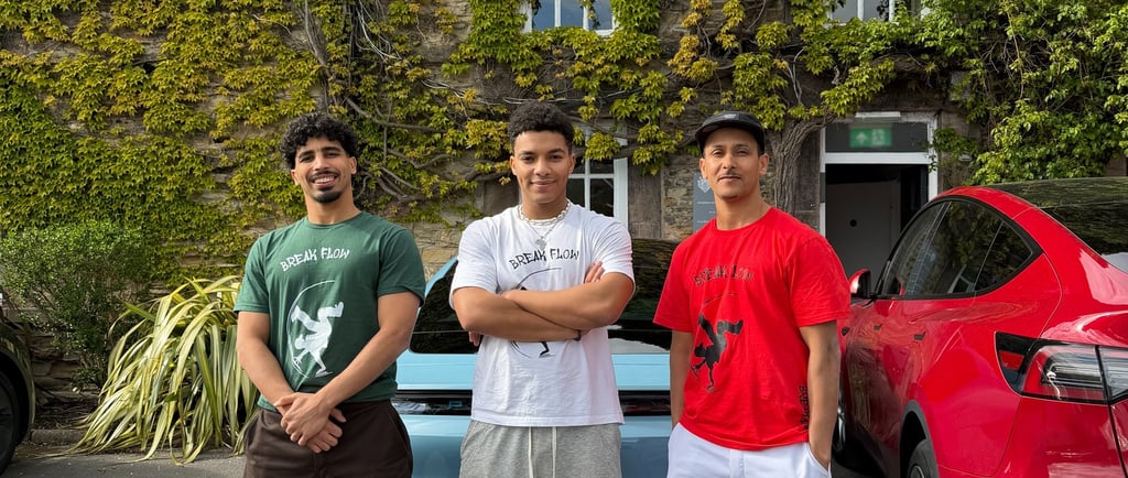 three break dancers stood outside an old building covered in ivy