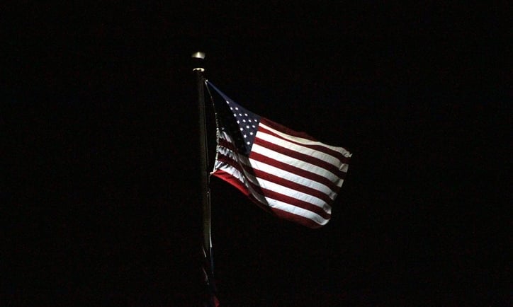a flag flying at night with lights on it