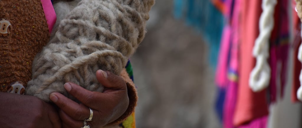 las manos de una artesana sosteniendo una madeja de lana sin hilar