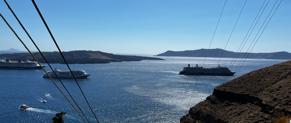 Cruise ships near a cliff off the shore of a Greek island.