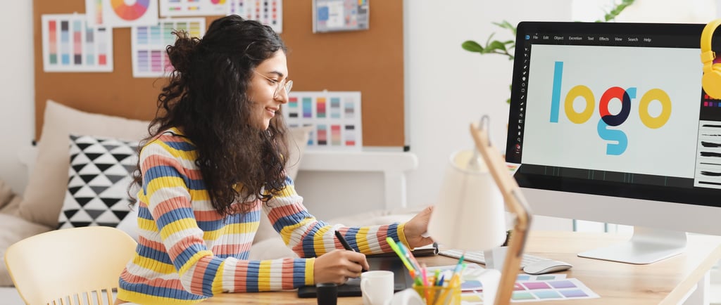 a woman sitting at a desk with a computer monitor and a laptop