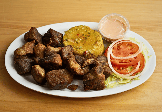 a plate of carne frita con mofongo y ensalada