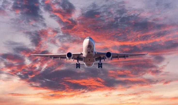 a plane taking off into the sunset
