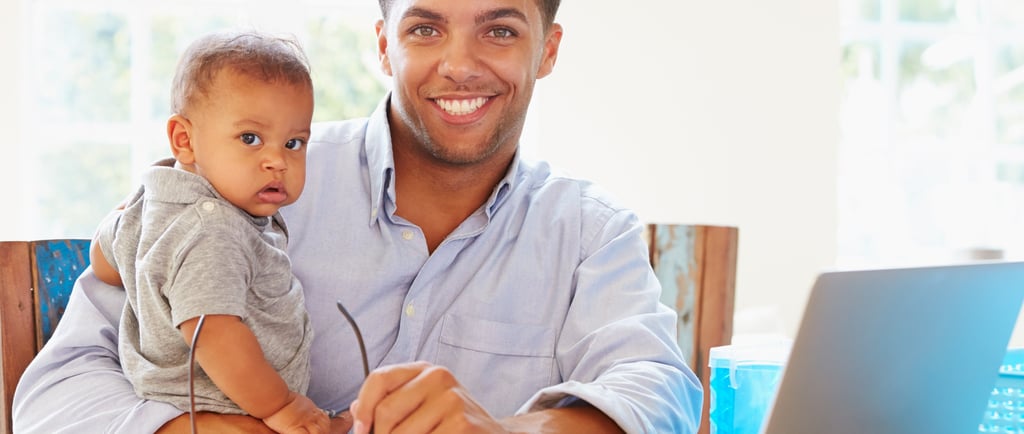 smiling father with infant son in front of laptop