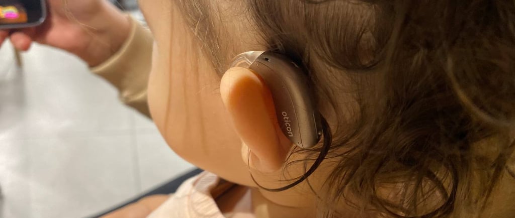 дитина в рожевому светрі зі слуховим апаратом