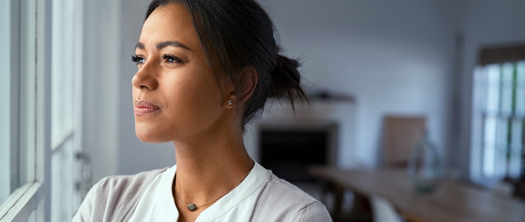 Pensive woman looking out the window, contemplating fertility journey