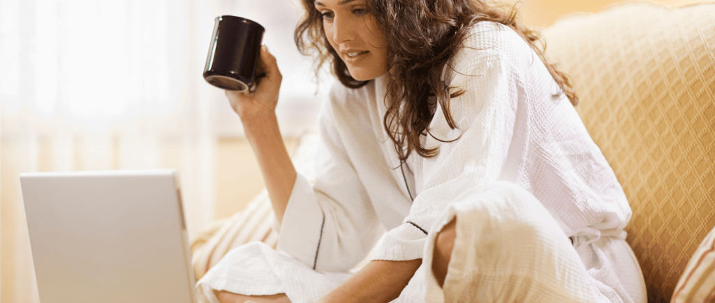 Woman comfortable at home on laptop with coffee mug, researching fertility options