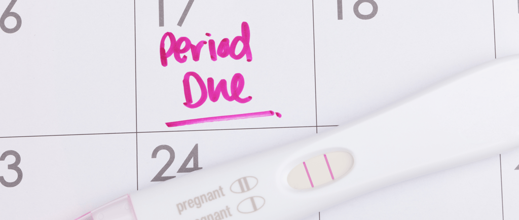 Calendar with "Period Due" written on it and a pregnancy test lying on top.