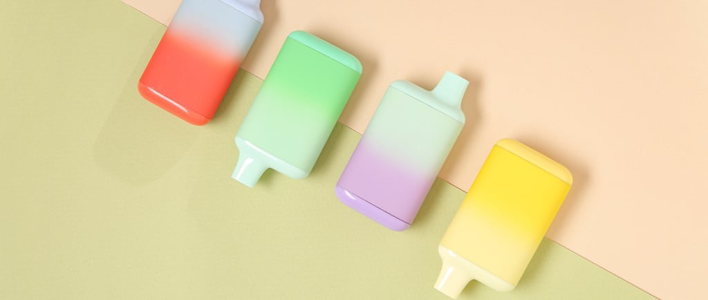Colorful pastel disposable vapes laid out on a soft color-blocked background.