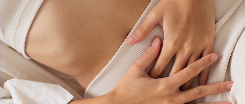 Woman resting hands on abdomen, symbolizing fertility awareness and care