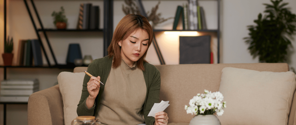 Woman calculating IVF costs at home with documents and calculator