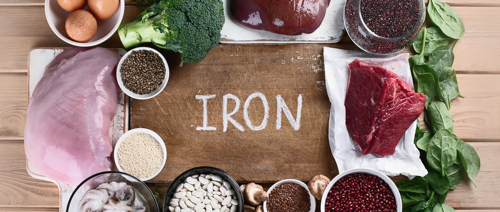 Flat lay of iron-rich foods like meat, spinach, beans, and seeds on a kitchen table