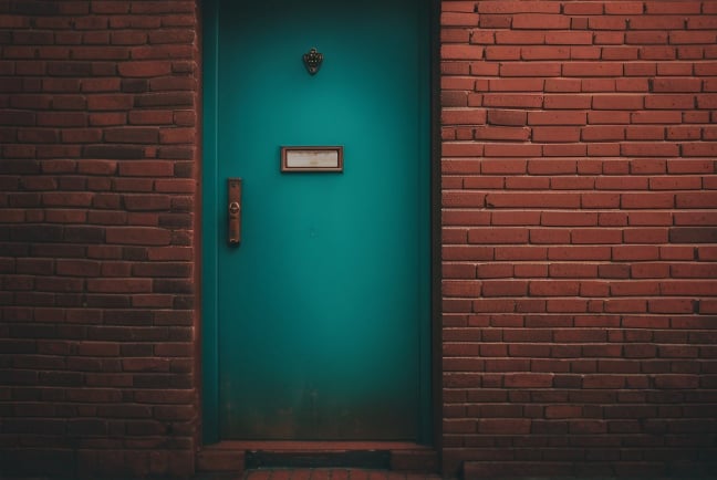 A bright green door set in a wall of red brick