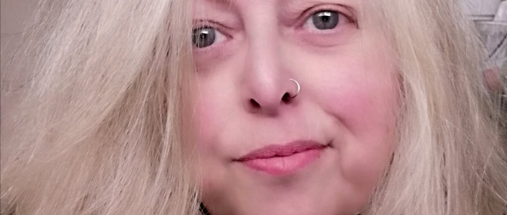 Image of a middle-aged woman with long blonde hair, big green eyes, and a nose ring