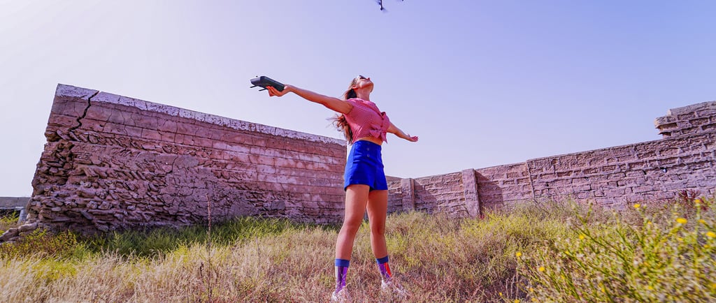 Woman in a filed flying a drone.