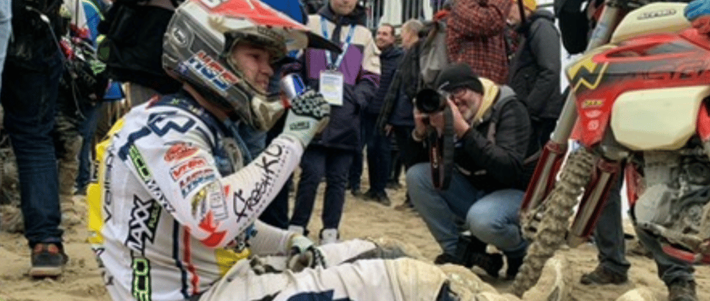 a man sitting on a dirt bike in the sand