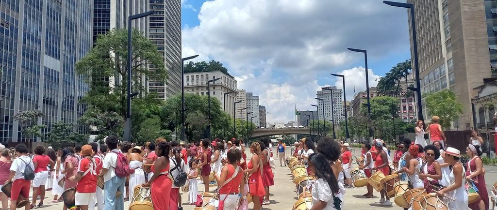 a group of people in red dresses and hats are playing drums