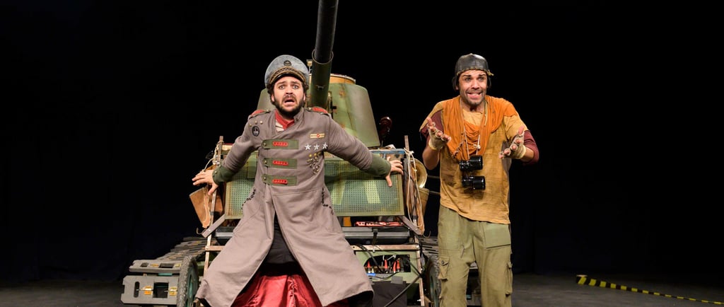 two men in military uniforms standing next to a tank