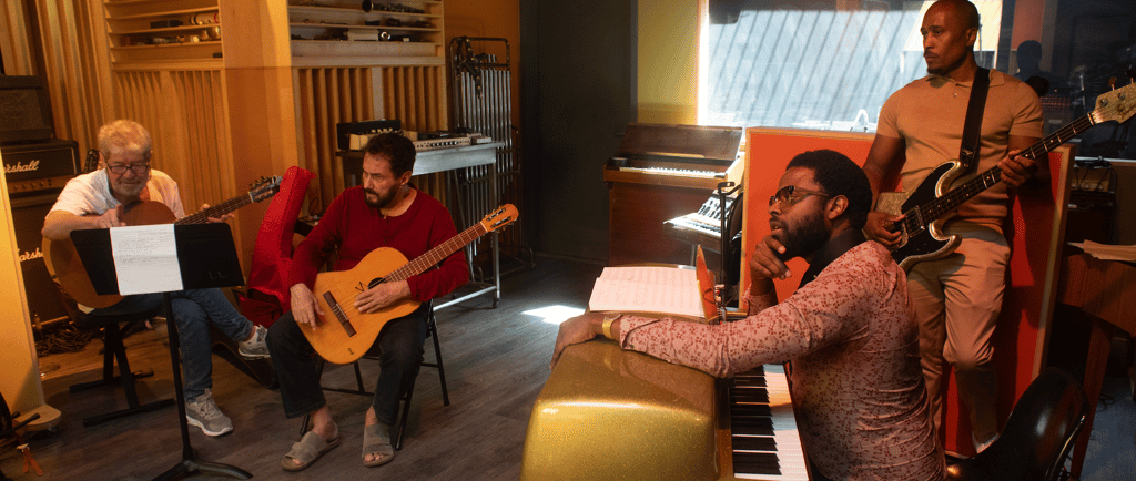 Musicians playing guitar, bass, and piano during a professional recording studio session.