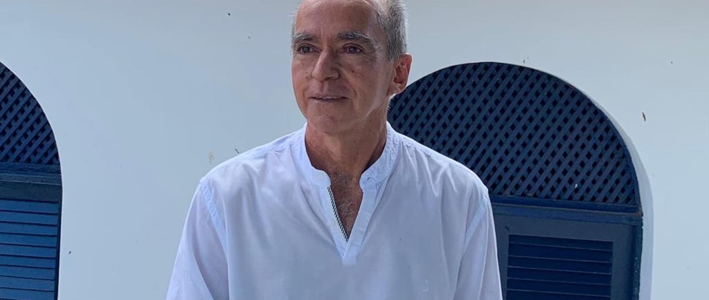 a man in a white shirt and jeans standing in front of a building