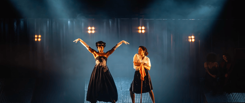 two women in black dresses standing on stage