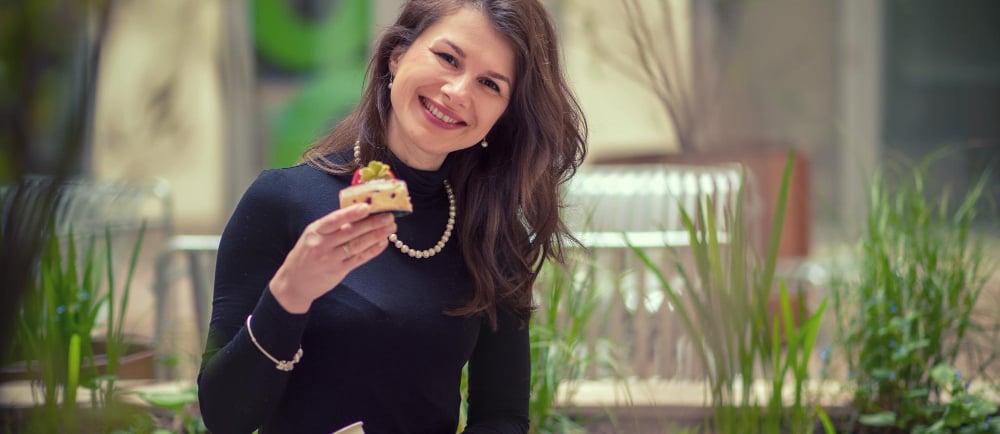 a sugar mommy sitting on a bench with a pastry