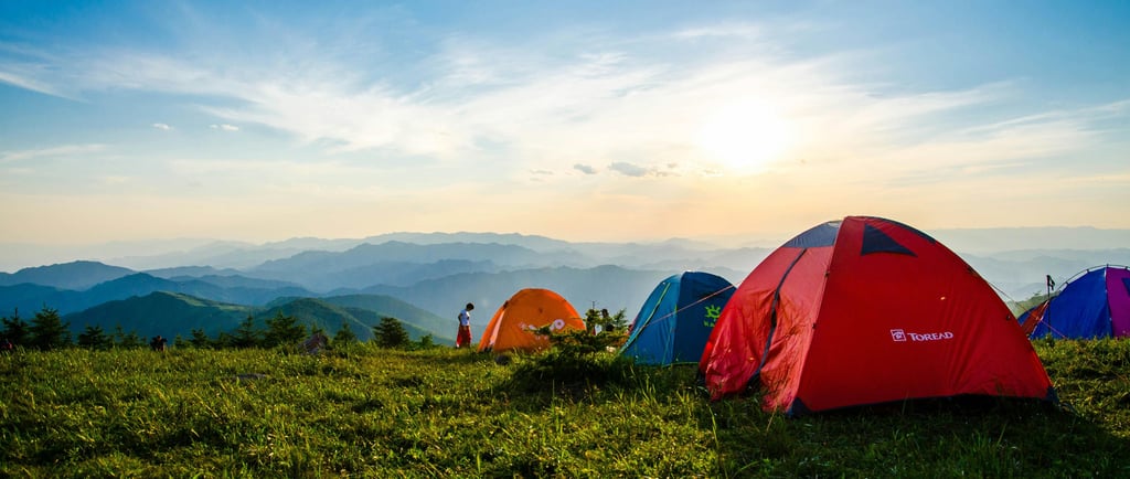 um grupo de tendas de acampamento montadas em uma colina gramada