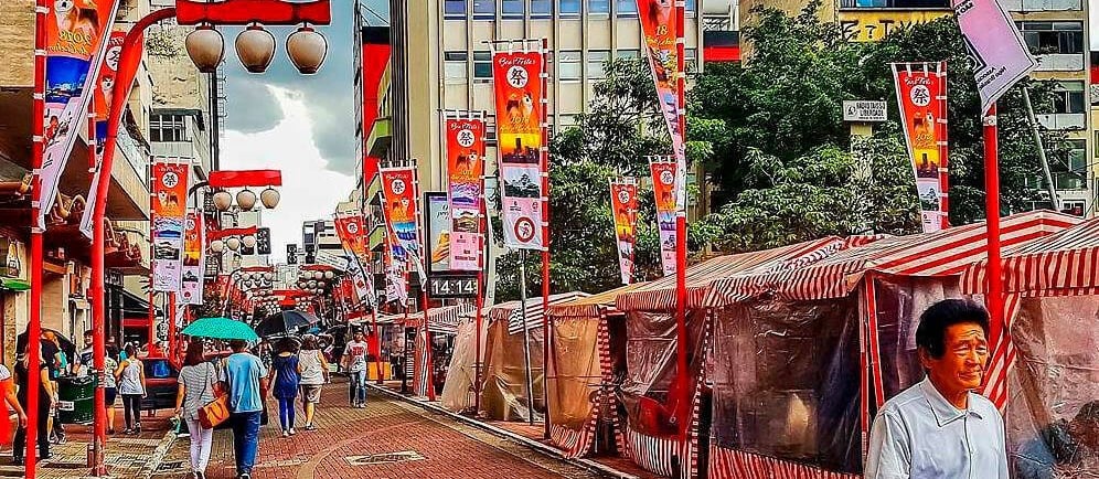 Rua Liberdade em São Paulo, com lanternas japonesas, bandeiras e uma feirinha.