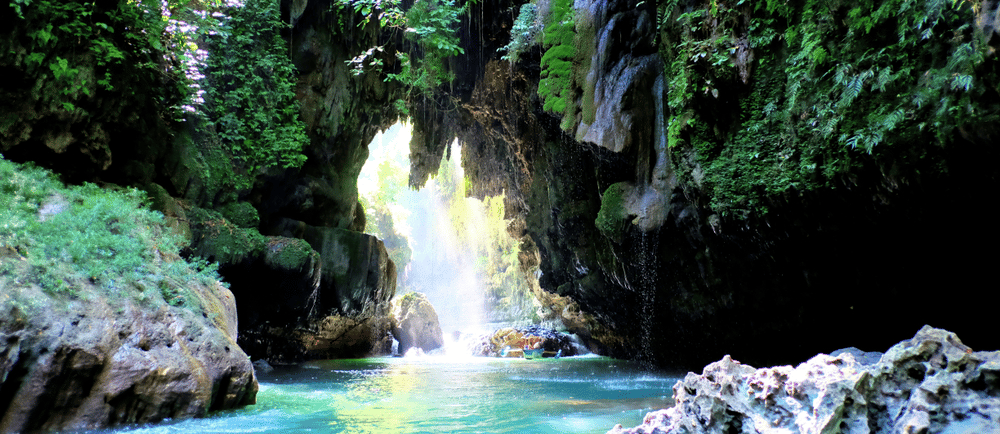 a waterfall flowing down a river with a boat in the background