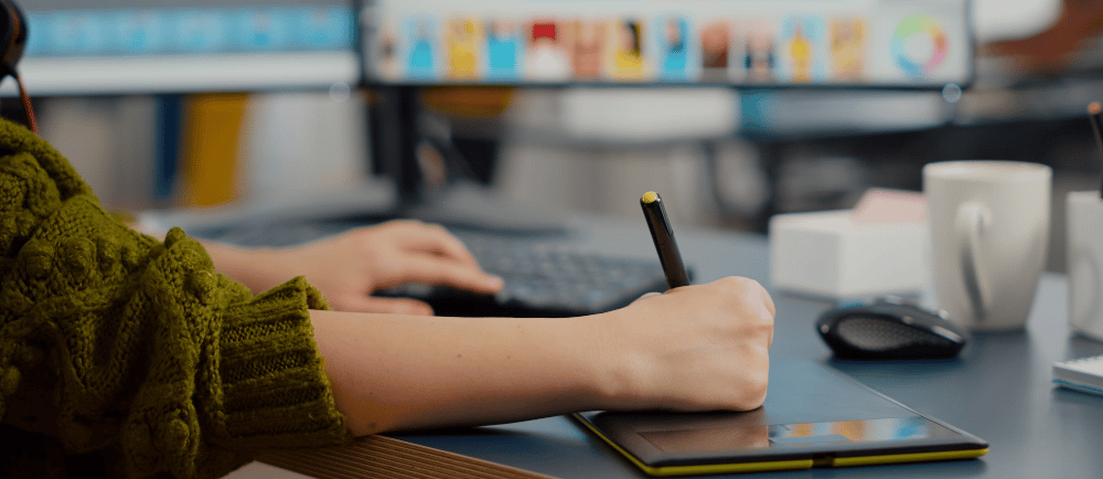 Designer usando tablet em frente a computador