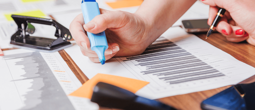 Mesa com materiais de escritório e mão com marca-texto