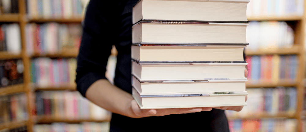 Mulher segurando uma pilha de livros em uma livraria
