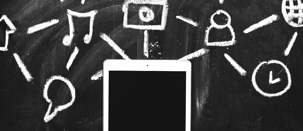 Um celular em cima de uma lousa com desenhos relacionados a marketing