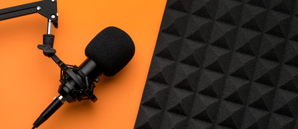 Imagem com um microfone e com o fundo laranja e preto