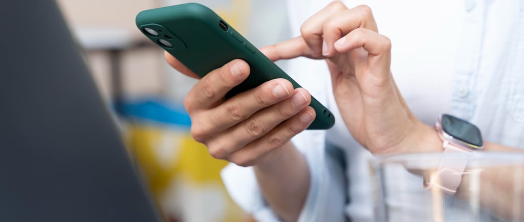 Mão da secretária de um advogado segurando um celular enquanto usa o WhatsApp Business